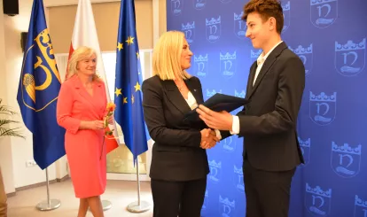 Wójt Agnieszka Powała  wręcza nagrodę jednemu ze stypendystów, na zdjęciu również Radna Teresa Iwona Bartosiewicz